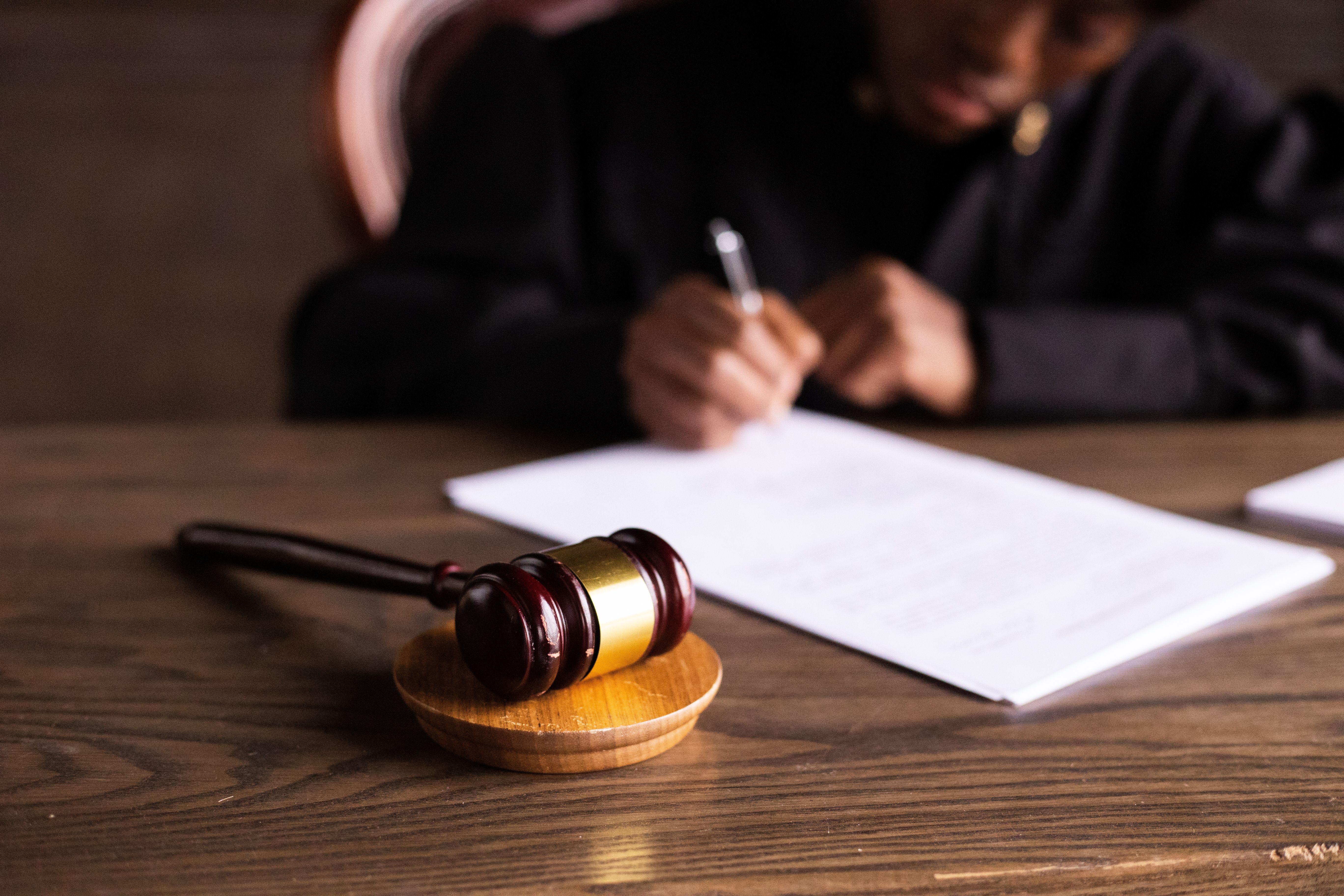 Judge signing documents at desk with a gavel symbolizing legal proceedings