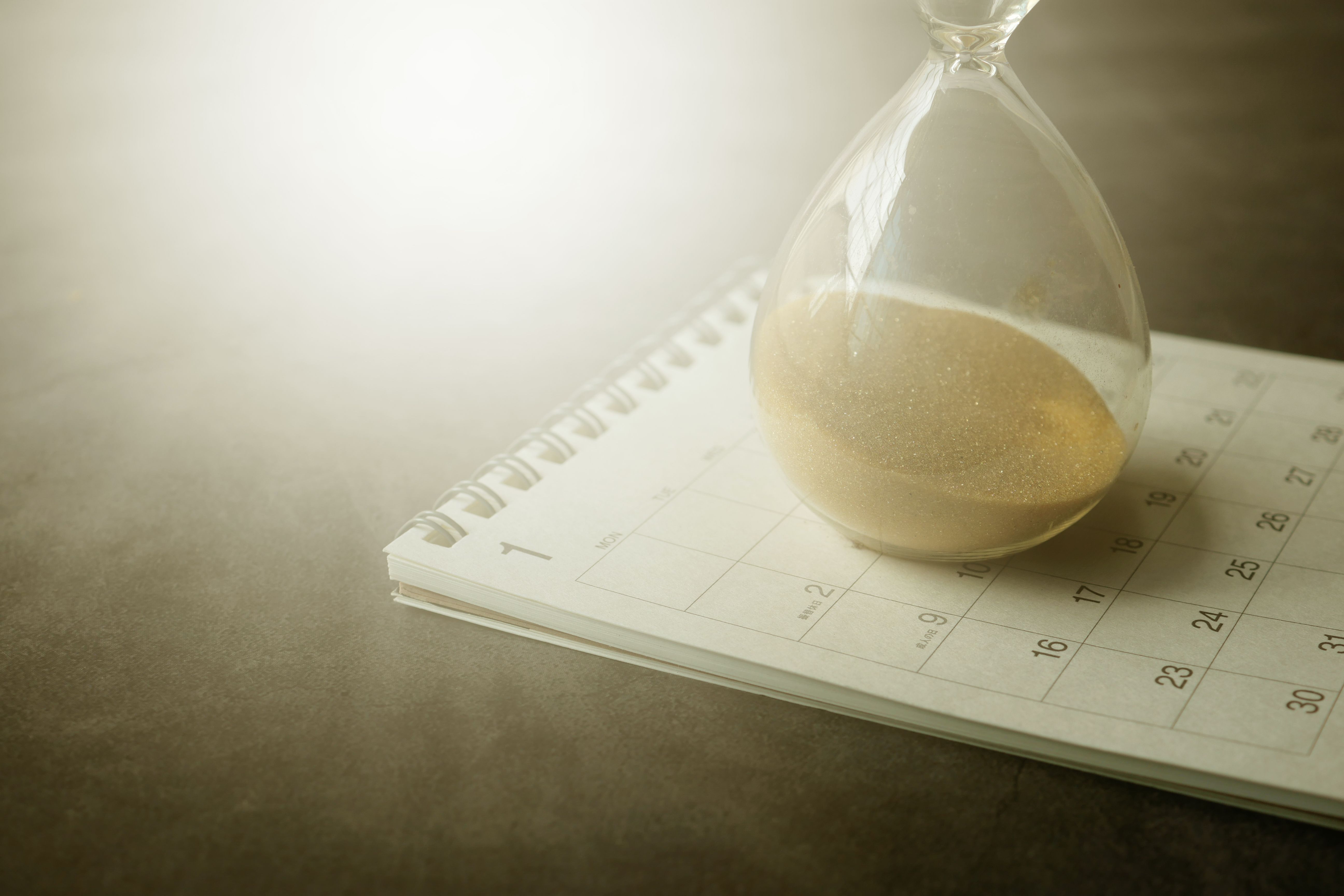Hourglass resting on a calendar representing the timeline and duration of a lawsuit