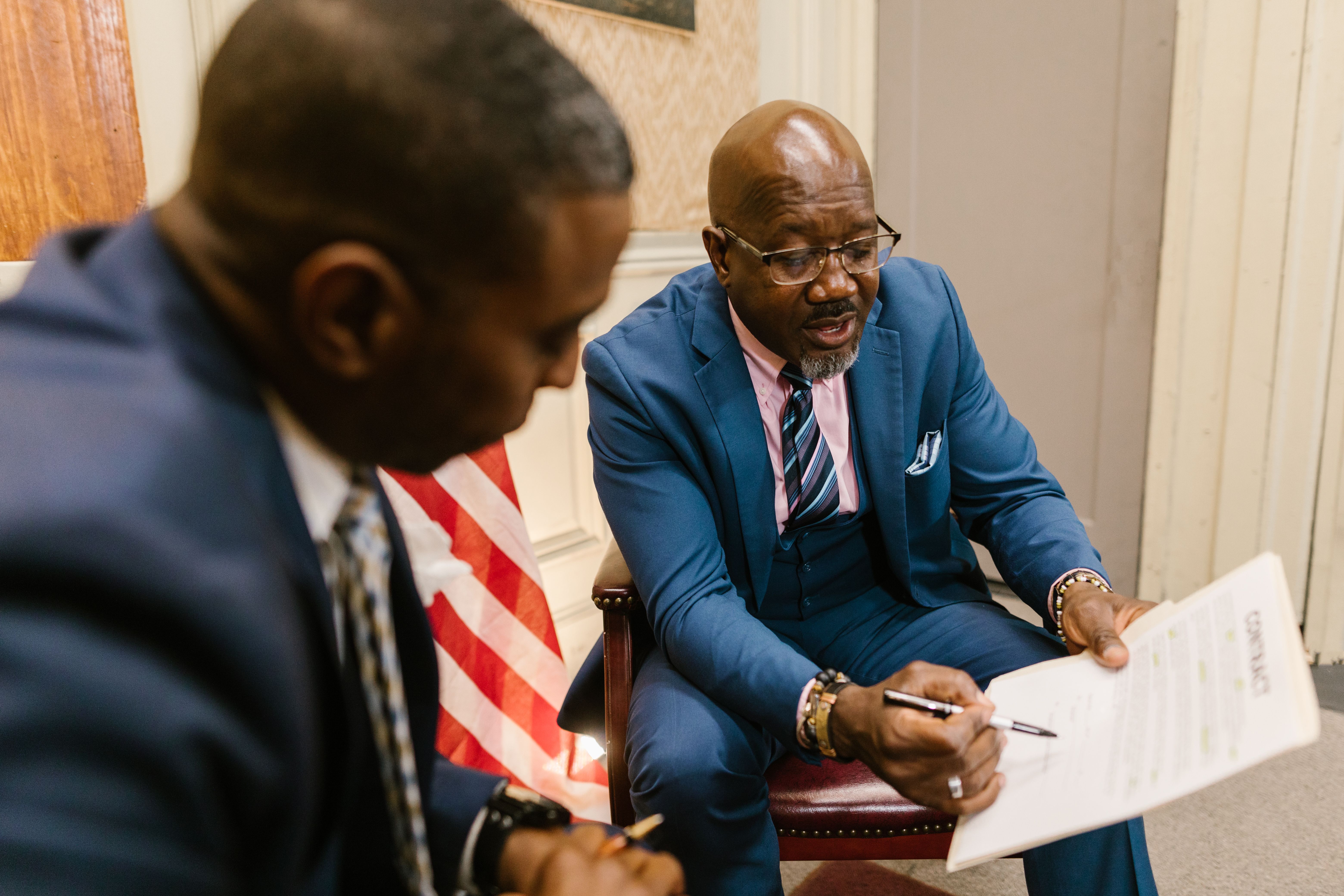 Two people reviewing and signing a legal contract in an office setting
