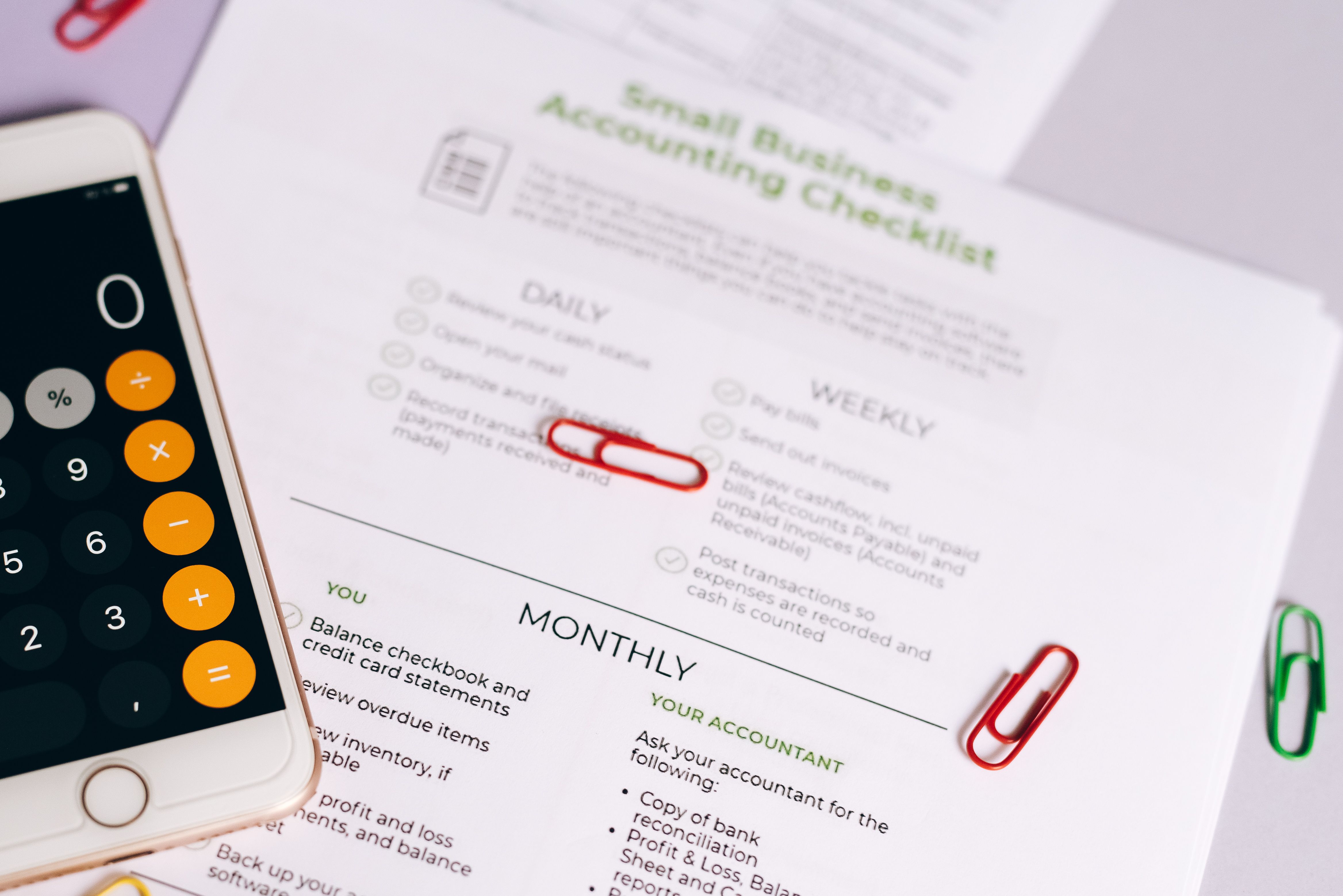 Checklist and calculator on a desk for evaluating small business accounting and financing decisions.